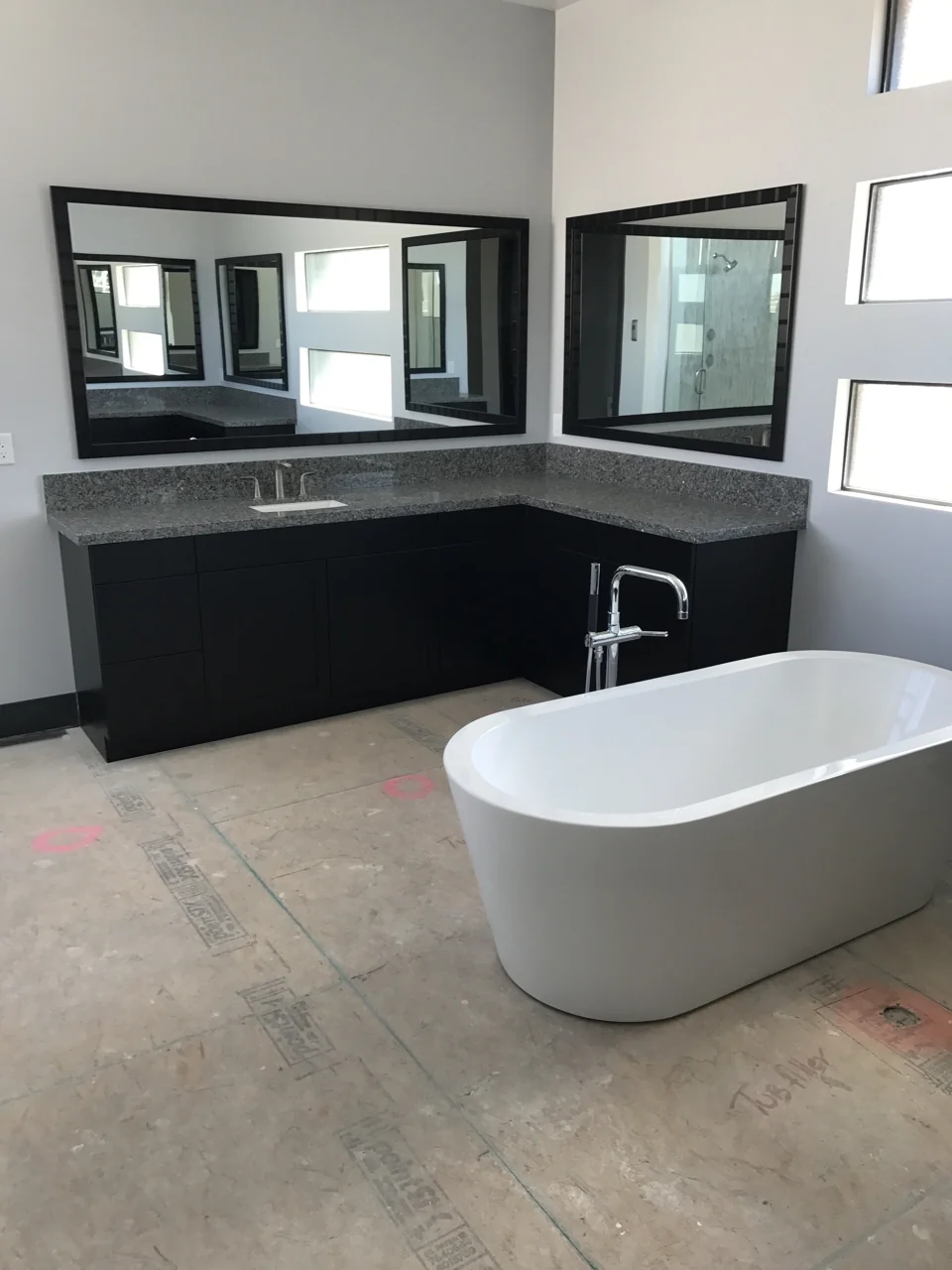 Work in progress: a freestanding tub and dark vanity cabinetry with exposed subfloor still visible.