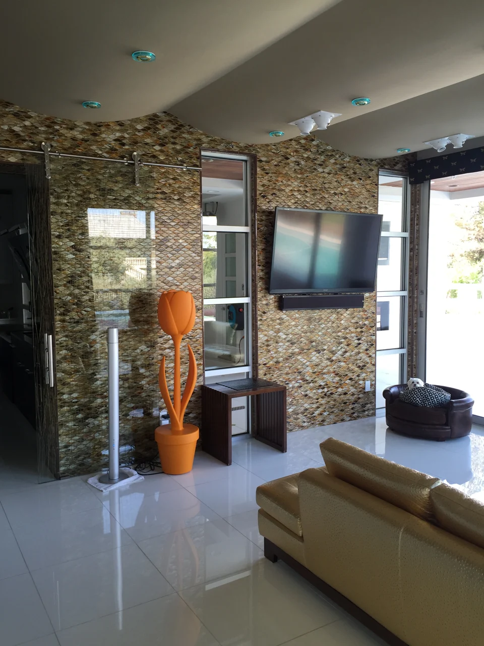 A patterned mosaic feature wall with integrated media and a sliding glass door.
