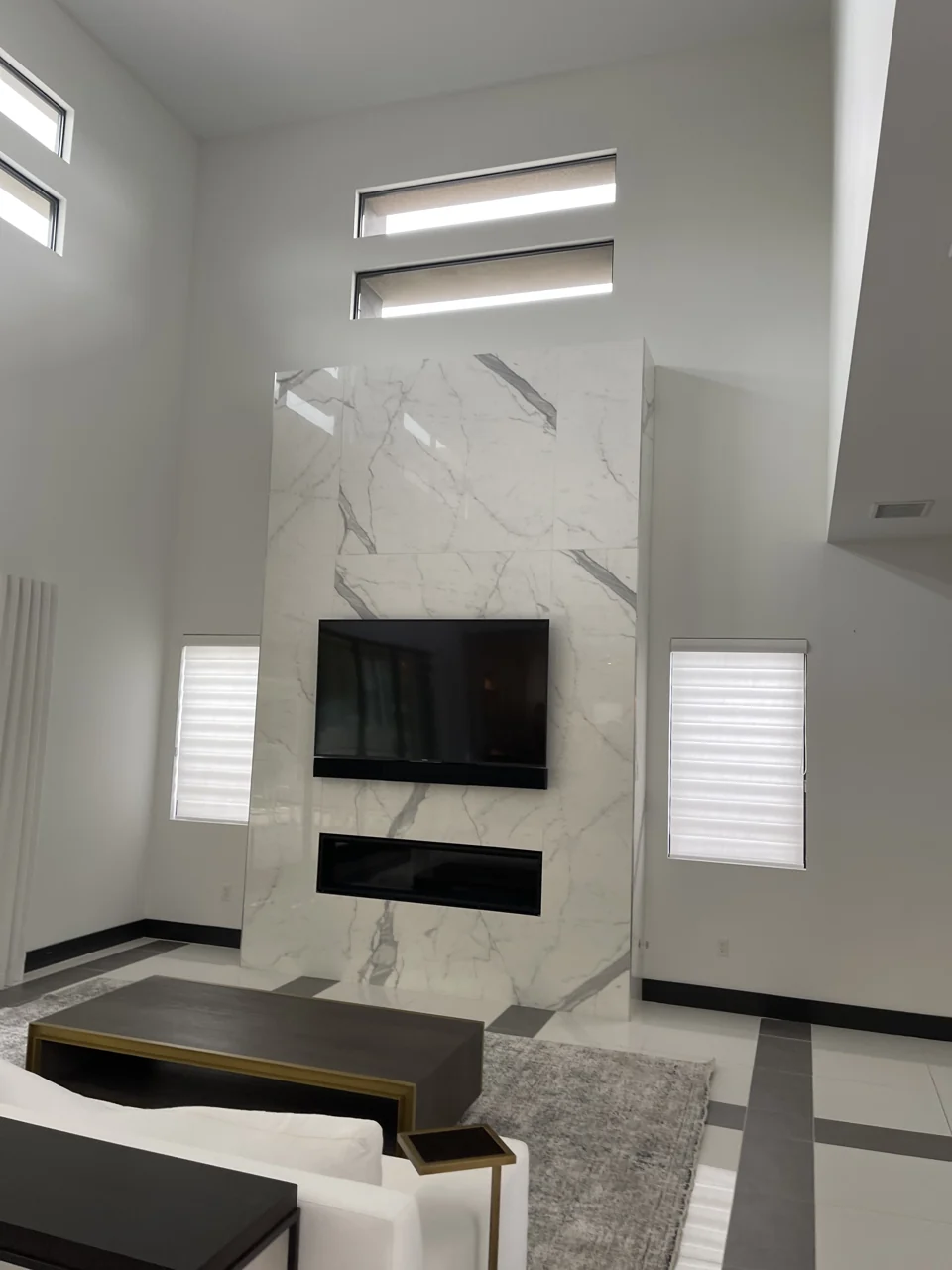 A tall veined-stone feature wall surrounding a television and linear fireplace.