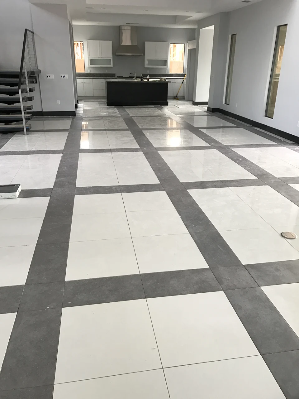A later construction view shows the geometric tile pattern extending toward the kitchen; finishing and cleanup are still underway.