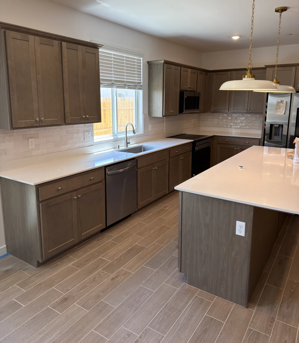 Wood cabinetry, white counters, a tiled backsplash, and brass pendant lighting.