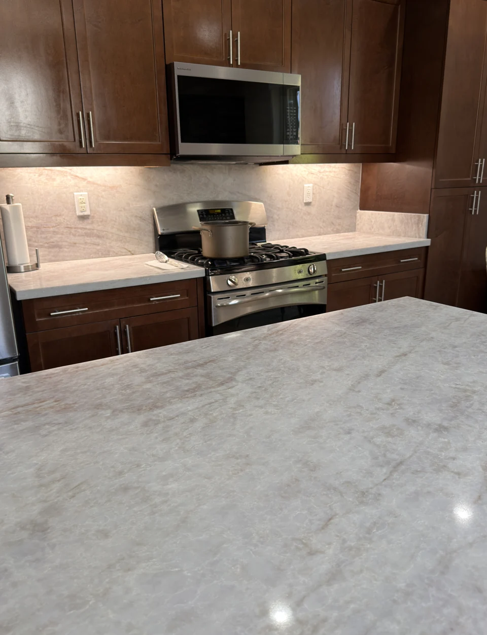 A pale stone island and matching backsplash paired with warm wood cabinetry.