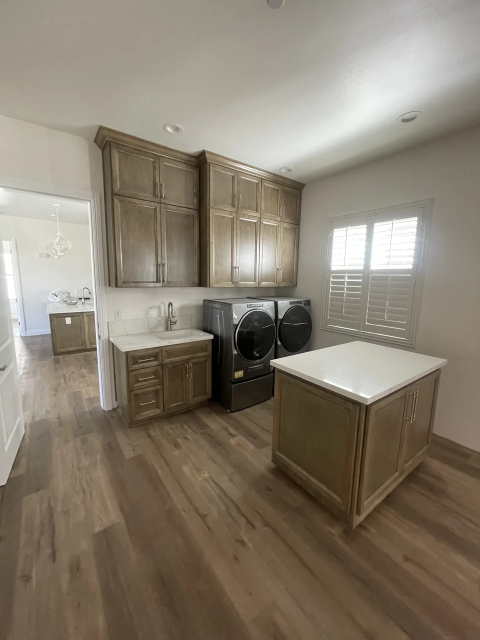 Wood laundry cabinetry, a utility sink, and a freestanding folding island.